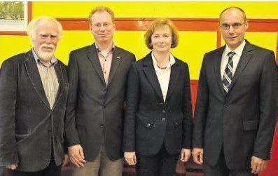 Vier Personen stehen nebeneinander vor einer gelben Wand während einer Fachveranstaltung zur stufenweisen Wiedereingliederung in Cuxhaven.