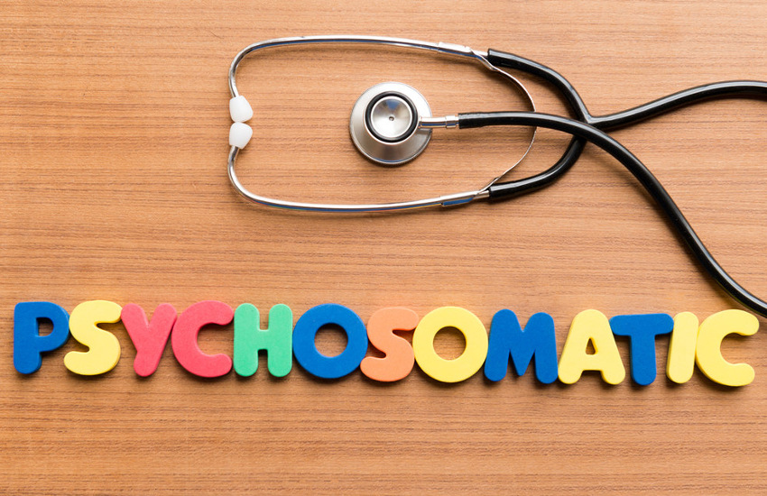 Buntgelegte Buchstaben formen das Wort „Psychosomatic“, daneben liegt ein Stethoskop auf einem Holztisch. Symbol für Psychosomatische Medizin und die Verbindung von Körper und Psyche.