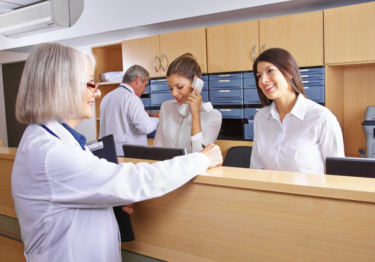 Rezeption einer psychosomatischen Versorgungspraxis mit medizinischen Fachangestellten im Gespräch mit Patienten und Ärzten im Hintergrund.