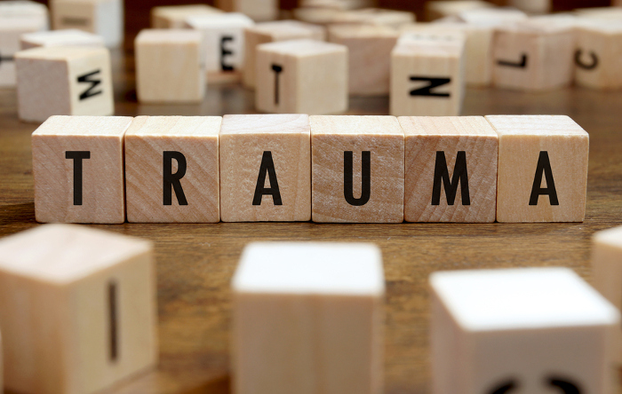 Holzklötze mit dem Wort „Trauma“ auf einem Holztisch – Symbolbild für psychische Verletzungen und Traumafolgen.