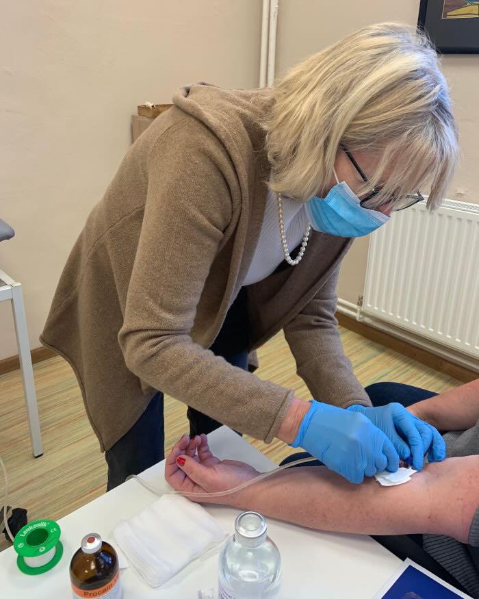 Eine Ärztin führt im MVZ Timmermann und Partner eine Neuraltherapie bzw. Infusionstherapie am Arm eines Patienten durch.