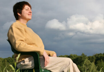 Frau sitzt entspannt im Freien – Symbolbild für Autogenes Training bei Timmermann & Partner