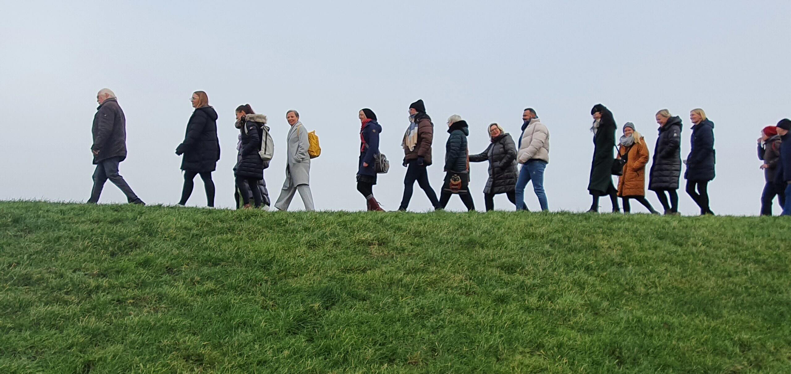 Mitarbeiter*innen des MVZ Timmermann und Partner spazieren bei sonnigem Wetter auf dem Deich während des Begrüßungstags im Februar 2023.