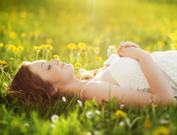Frau liegt entspannt im Gras – Symbolbild für Autogenes Training und Entspannung