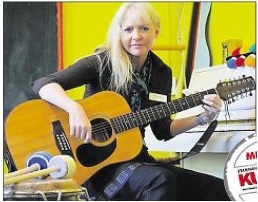 Kerstin Duken, Diplom-Musiktherapeutin, sitzt mit einer Gitarre in einem Therapieraum und spielt Musik für ihre Patienten.