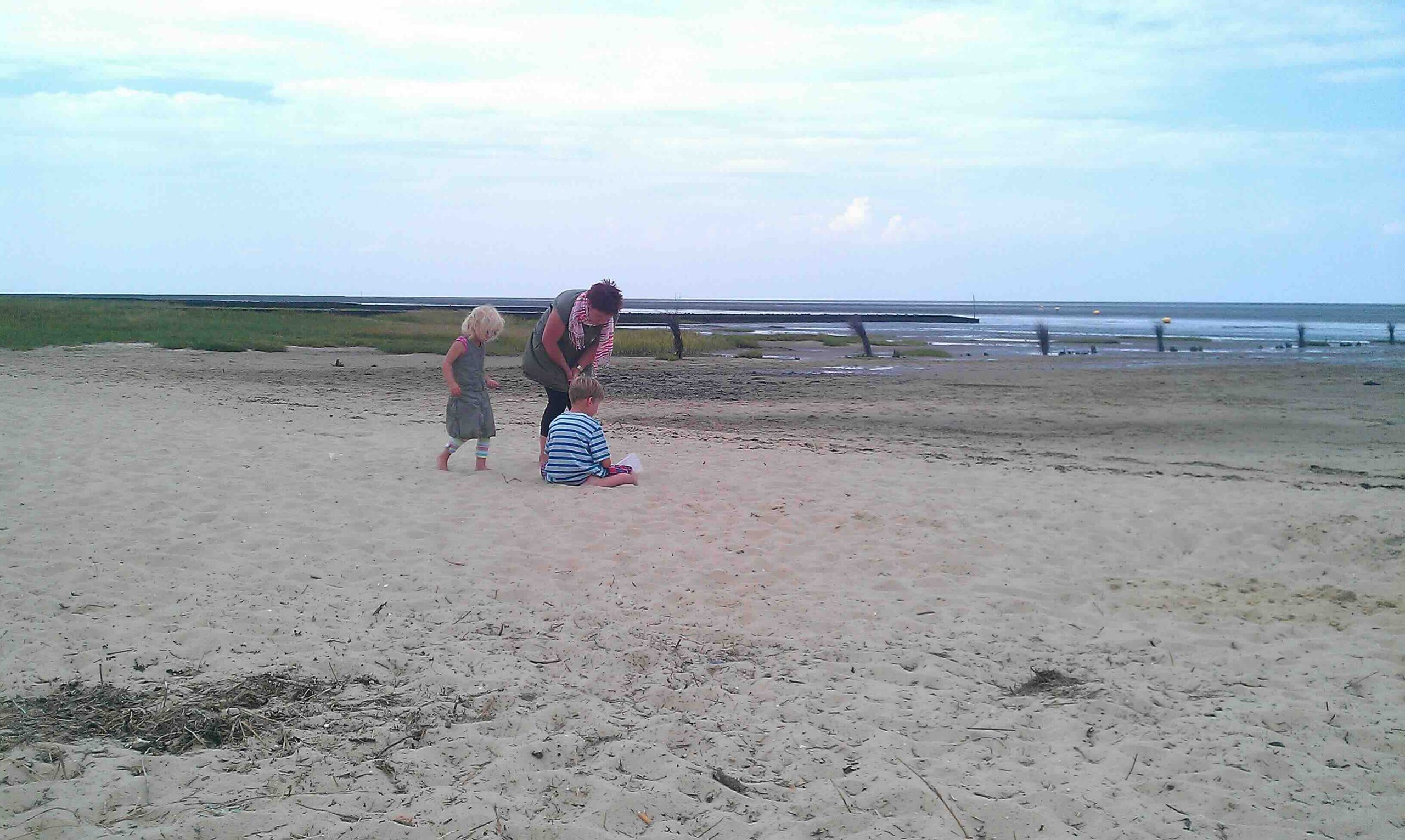 Eine Frau betreut zwei Kinder am Strand – Symbolbild für die Herausforderungen und Hoffnungen im Kindes- und Jugendalter.
