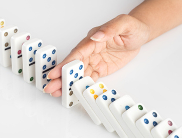 Hand stoppt fallende Dominosteine – Symbolbild für Prävention und Vorsorge im MVZ Timmermann & Partner