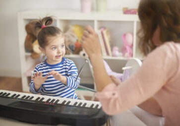 Kind spielt mit Therapeutin am Keyboard – Symbolbild für Musiktherapie im MVZ Timmermann & Partner